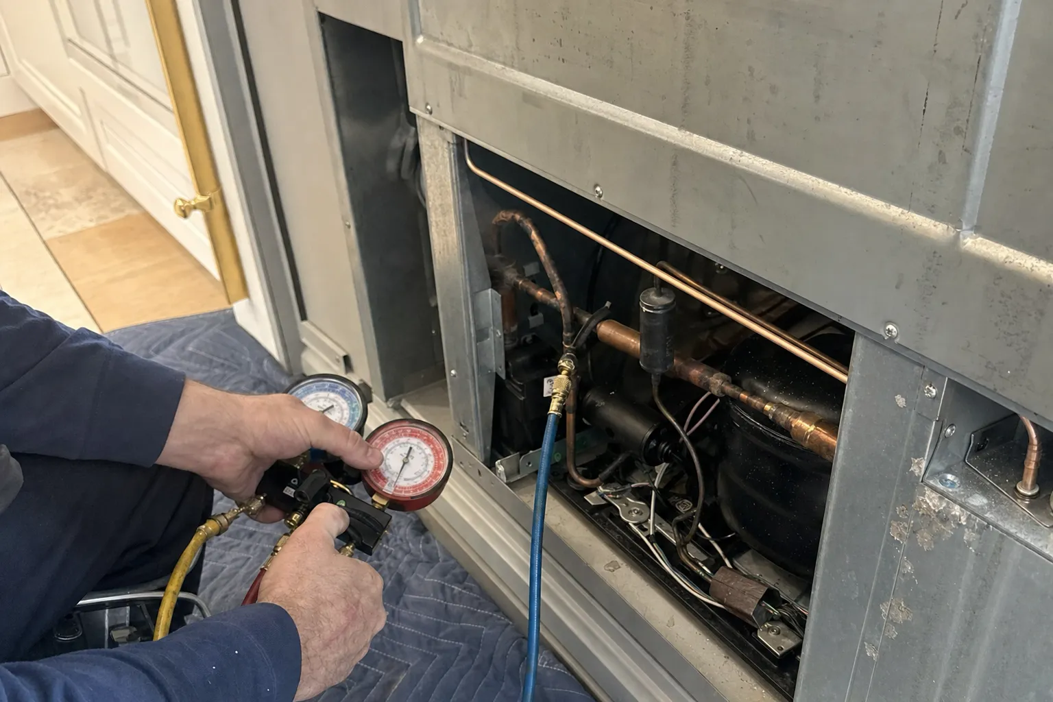 Manifold gauges connected to the sealed system in the machine compartment of a built-in refrigerator